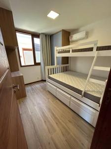 a bedroom with two bunk beds and a wooden floor at Village 115 Barra Grande (Viva Barra) in Marau