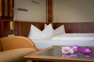 a hotel room with two beds and a table with flowers at Das Allgäu in Maierhöfen
