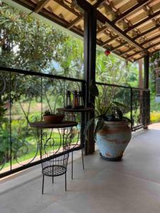 een veranda met een plant en een tafel en een vaas bij Villa Pietá in Brumadinho