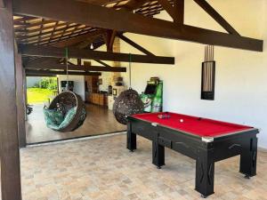 une pièce avec une table de billard rouge et des balançoires dans l'établissement 6 Suites, banheira, Piscina, no coração da Região dos Lagos, à São Pedro da Aldeia
