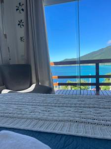 um quarto com uma cama e vista para o oceano em Loft Pelicano Prainhas- Pontal do Atalaia- Para Casal em Arraial do Cabo