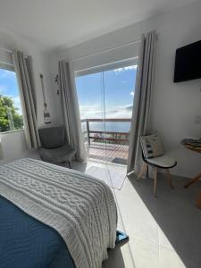 um quarto com uma cama e vista para o oceano em Loft Pelicano Prainhas- Pontal do Atalaia- Para Casal em Arraial do Cabo