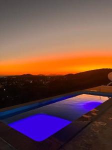 une piscine avec un coucher de soleil en arrière-plan dans l'établissement 6 Suites, banheira, Piscina, no coração da Região dos Lagos, à São Pedro da Aldeia