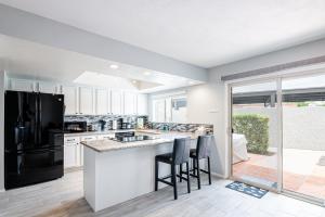 a kitchen with white cabinets and a black refrigerator at Scottsdale Old Town Haven, Walk To Old Town & Fashion Square Mall, Pool & Concierge Service! in Scottsdale