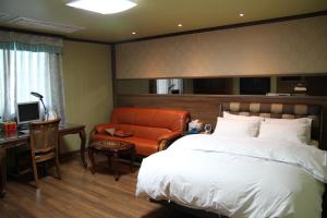 a bedroom with a bed and a desk and a chair at Gunsan Western Hotel in Gunsan-si