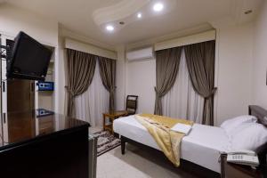a hotel room with a bed and a flat screen tv at Badr Hotel Assiut in Asyut