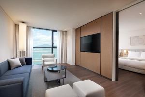 a hotel room with a couch and a bed and a television at Shilla Stay Plus Ihotewoo in Jeju