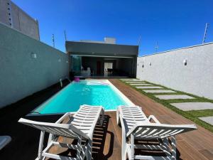 uma piscina com espreguiçadeiras ao lado de uma casa em Chácara Espanha em Maringá