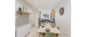 uma sala de jantar com uma mesa longa e cadeiras verdes em Essex Vibes: Modern, Funky, & Spacious 4-Bed House em Southend-on-Sea