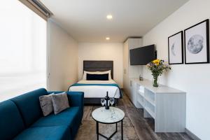 um quarto de hotel com uma cama e um sofá em Torre Acqua Lofts - Downtown Bogota em Bogotá
