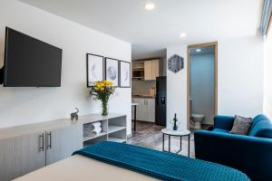 a living room with a blue couch and a tv at Torre Acqua Lofts - Downtown Bogota in Bogotá