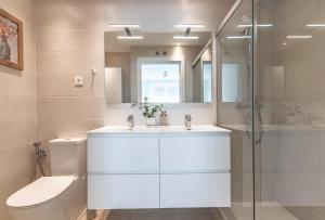 een badkamer met een wastafel, een toilet en een spiegel bij AkomodaT en nuevo y precioso en Algorta con parking in Getxo +16 foto's