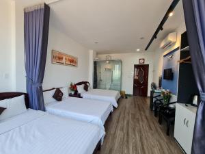 a hotel room with three beds with blue curtains at SUN HOTEL in Hue