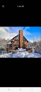 Una foto de una casa en la nieve en L'hêtre au Sommet (gîte) en Sainte Anne des Lacs