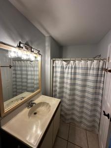 y baño con lavabo y ducha con espejo. en Ocean City, MD Waterfront Villa, en Ocean City