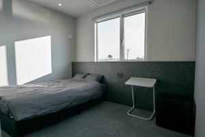 a bedroom with a bed and a table and two windows at NEW HUMBER 