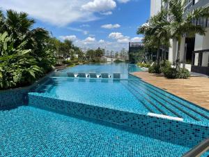een groot zwembad met stoelen en palmbomen bij Greenfield Residence Sunway Subang 10 Pax 3R2B with Internet in Petaling Jaya