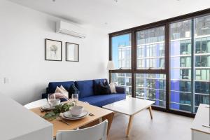 a living room with a blue couch and a table at A Cozy & Comfy 2BR Apt Up in the Clouds Near CBD in Melbourne