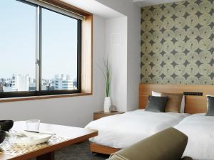 a bedroom with two beds and a table and a window at MIMARU Tokyo Asakusa Station in Tokyo