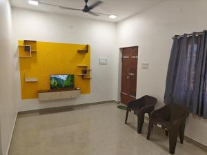 una stanza con due sedie e una parete gialla di Thirunallar Heaven Homes a Tirunallār