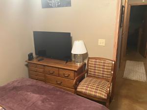 a bedroom with a dresser with a tv and a chair at And Boots Start Knocking in Stillwater