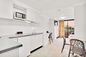 a kitchen with white cabinets and chairs and a table at Carlton Lygon Lodge - Close to Melbourne Uni in Melbourne
