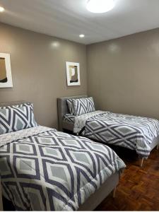 ein Zimmer mit 2 Betten und einem Stuhl darin in der Unterkunft Bonel Townhouse Tagaytay in Alfonso