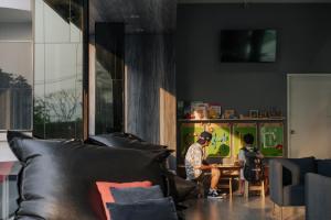 two people sitting at a table in a living room at Mittapan Hotel in Kanchanaburi