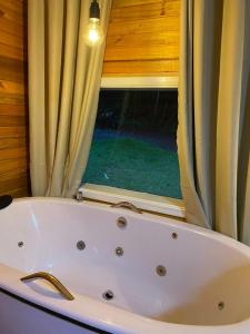 a bath tub in a bathroom with a window at Chalés Canto da Serra in Monte Verde