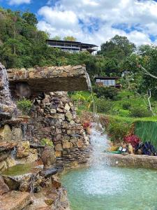 einen Wasserfall in einem Garten mit einer Steinmauer in der Unterkunft Natubri Ecohotel Habitacion VIP in San Francisco