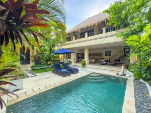 a swimming pool in front of a house with a resort at Villa Bugis Kayu Aya Seminyak in Seminyak