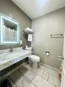 a bathroom with a toilet and a sink and a mirror at Villa Court Inn Oroville in Oroville