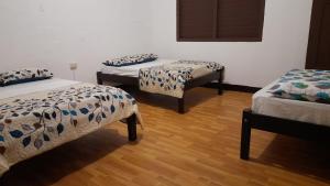 three beds in a room with wooden floors at Hotel Sansivar in El Venado