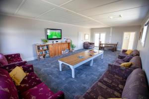 sala de estar con sofás, mesa y TV en Tāhuna Beach Holiday Park en Nelson