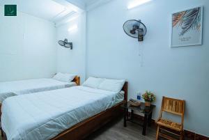2 Betten in einem Zimmer mit einem Stuhl und einem Tisch in der Unterkunft SAMI Coffee Hotel in Dong Hoi