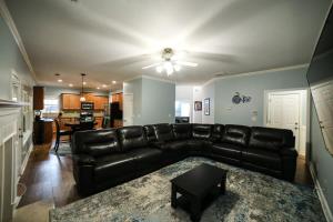a living room with a leather couch and a table at Big 5 Bdrm Private Hot Tub Pool Table Near Shops in Loganville