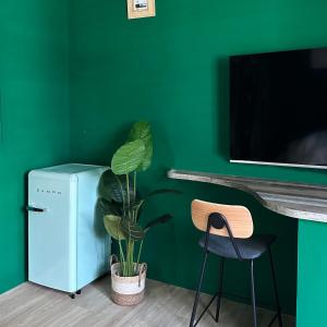 a green wall with a small refrigerator and a plant at 虎尾慢遊 in Huwei