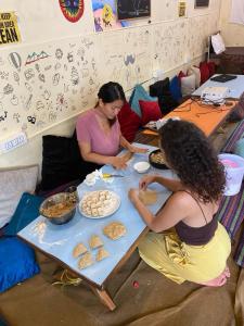 dos mujeres sentadas en una mesa haciendo pan en One More Night hostel and community living en McLeod Ganj
