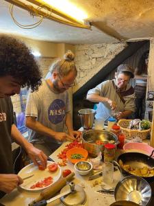 un grupo de personas de pie alrededor de una mesa preparando comida en One More Night hostel and community living en McLeod Ganj