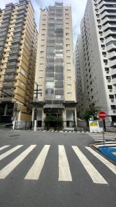 an empty street with two tall buildings and a stop sign at Joia Da Pitangueiras in Guarujá