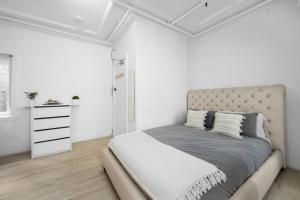 a white bedroom with a bed and a dresser at Urban retreat in Potts Point in Sydney