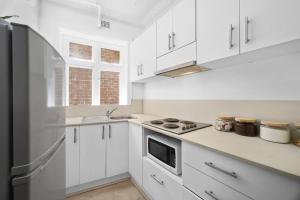 een keuken met witte kasten en een zwarte koelkast bij Urban retreat in Potts Point in Sydney