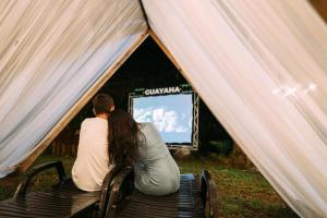 two people sitting in a tent watching a tv at Hotel Kopal in Lanquín