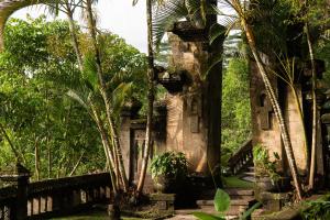 un vieux bâtiment avec des palmiers devant lui dans l'établissement Puri Wulandari A Boutique Resort & Spa - CHSE Certified, à Ubud