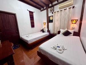 two beds in a hotel room with towels on them at Rattana Guesthouse in Luang Prabang