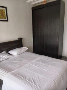 1 dormitorio con cama blanca y puerta de madera en Apto 3 alcobas, Tercer piso Norte de Cali, en Cali