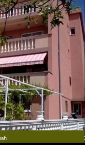 a large pink building with a red awning at Apartman Tihana in Crikvenica