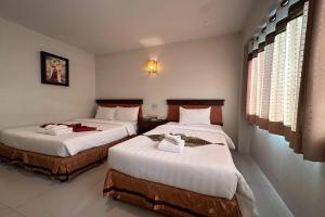um quarto de hotel com duas camas com lençóis brancos em Chiangrai Grand Room Hotel em Chiang Rai