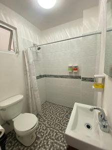 La salle de bains blanche est pourvue de toilettes et d'un lavabo. dans l'établissement Hotel Posada Jardín Aguascalientes, à Aguascalientes