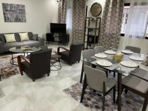 ein Wohnzimmer mit einem Tisch, Stühlen und einem Sofa in der Unterkunft Appartement meublé 3 chambres salon avec piscine jardin au virage in Dakar